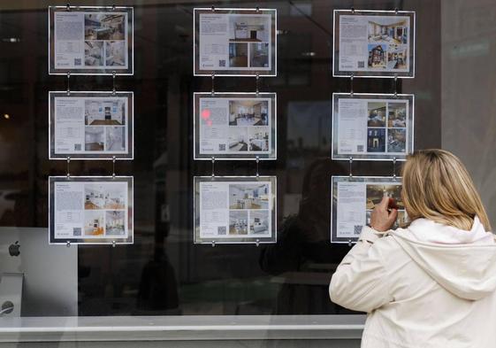 Una mujer observa ofertas de alquiler de viviendas en una inmobiliaria.
