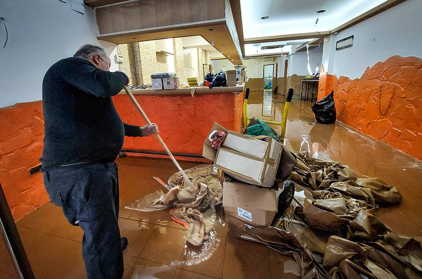 Un vecino recoge los objetos dañados por la pasada inundación en Erandio.