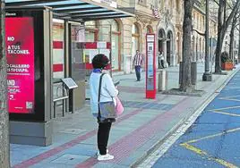 Una usuaria espera el autobús en la parada del Edificio Sota.