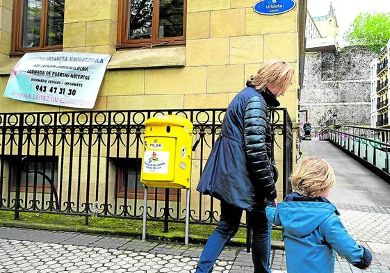 Una mujer se acerca con un niño de la mano a la entrada de la haurreskola de Urbieta Urdaneta, en Donostia.