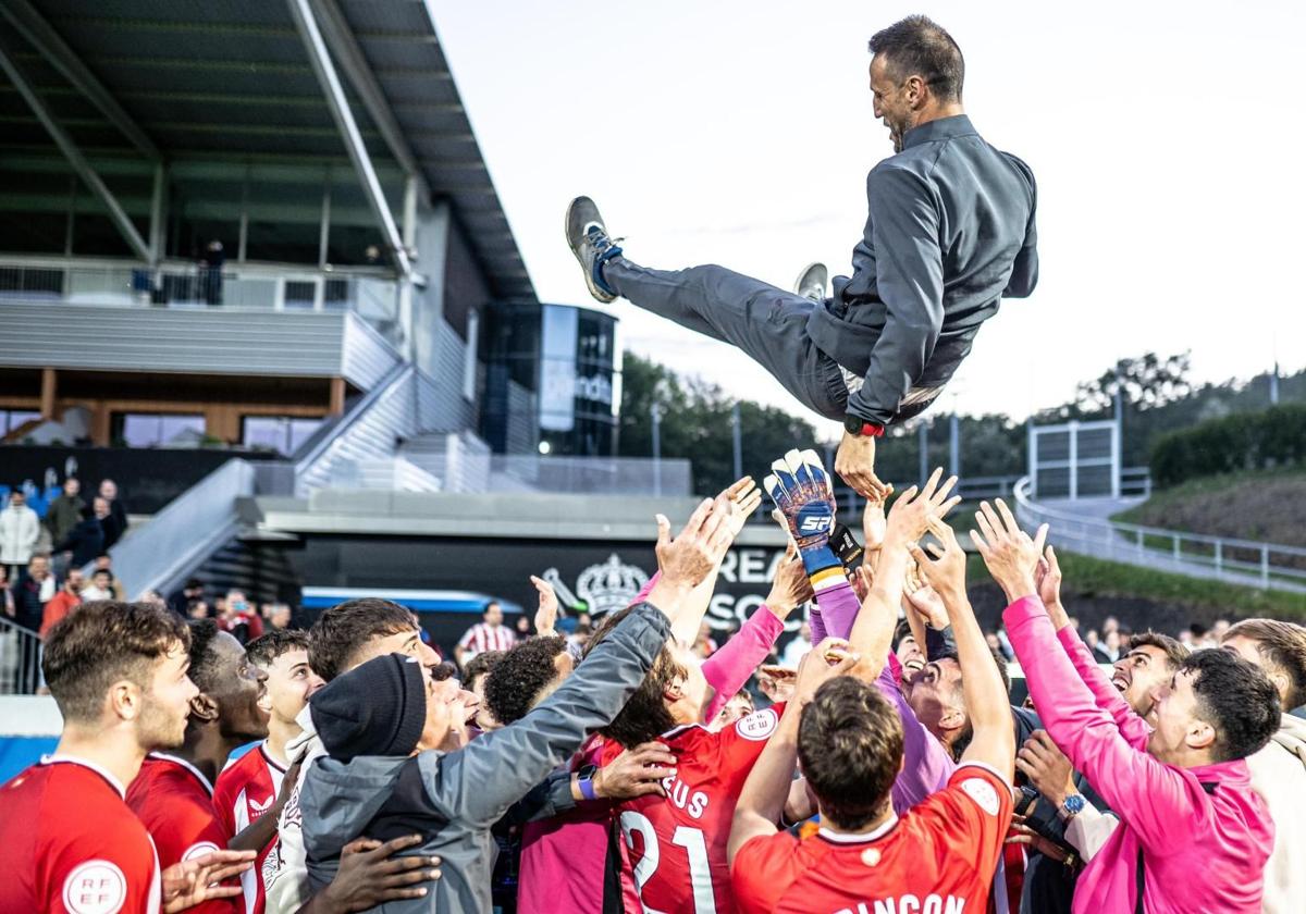 Los futbolistas mantean a Carlos Gurpegui.