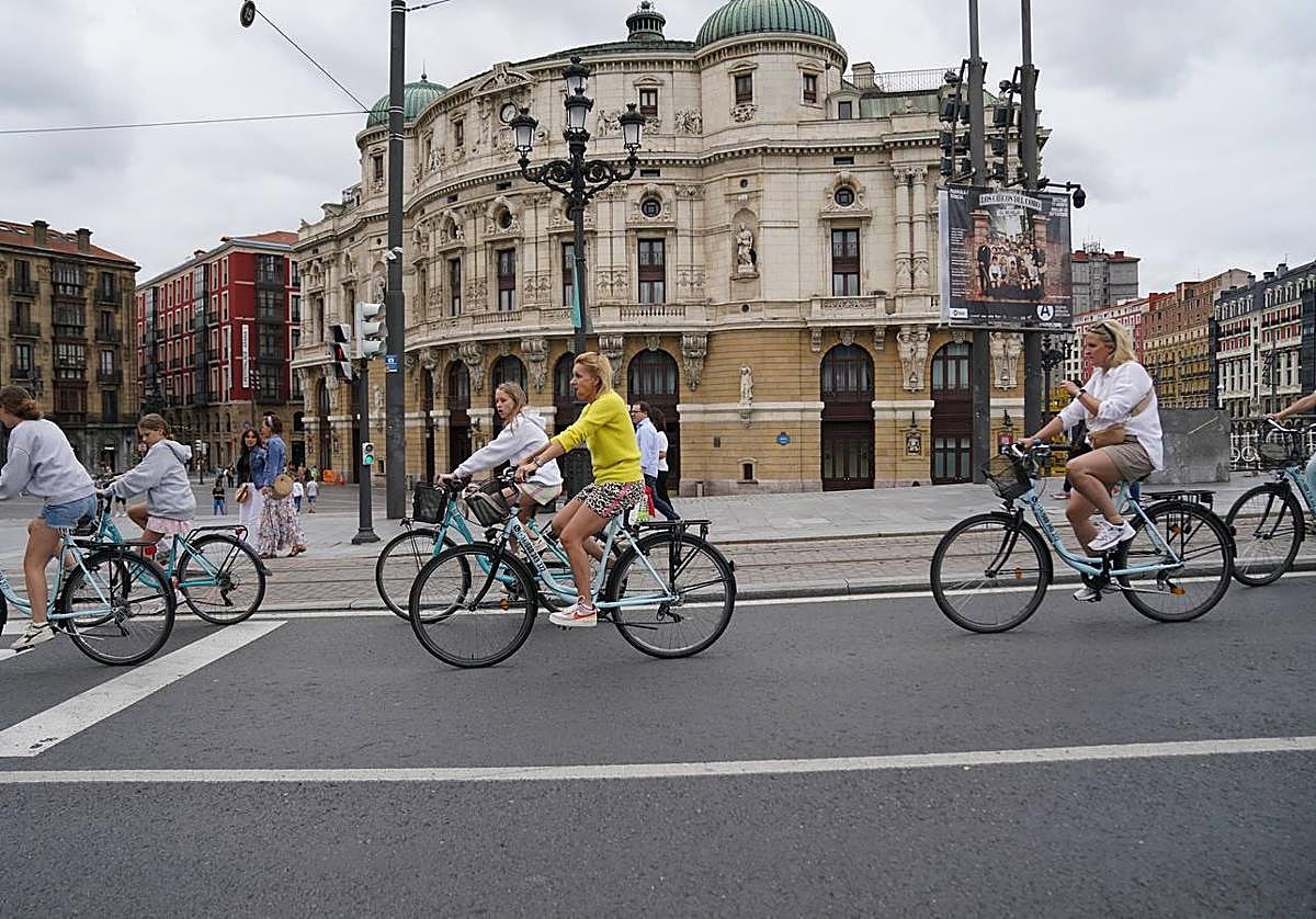 Turistas foráneos circulan en bicicleta por las inmediaciones del teatro Arriaga de Bilbao.