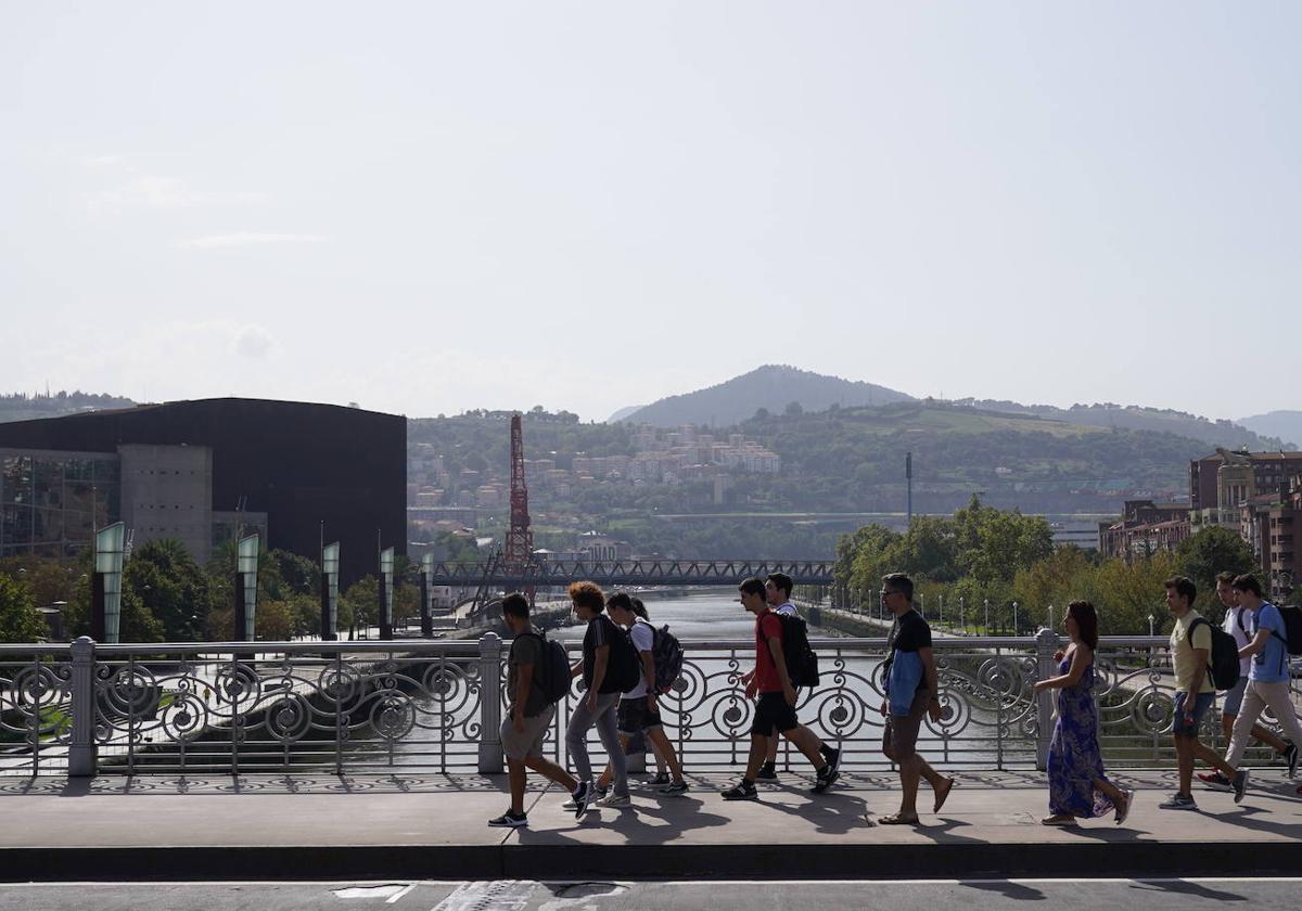 Un grupo de jóvenes cruza el puente de Deusto.