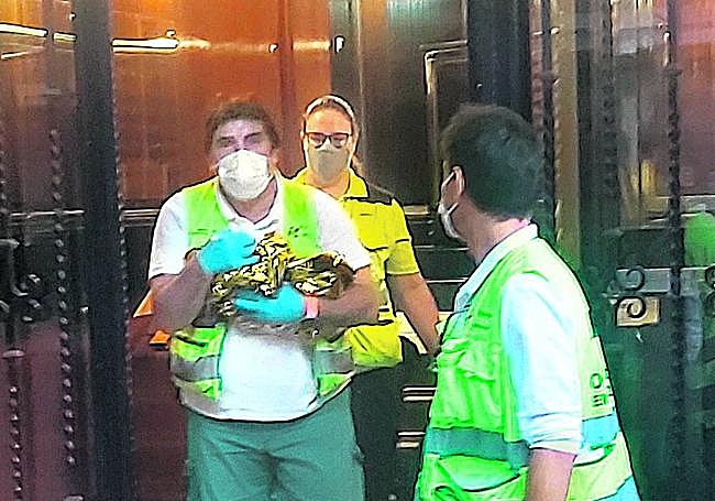 Imagen del momento en el que un sanitario recoge al bebé del portal de Santurtzu en el que fue abandonado.
