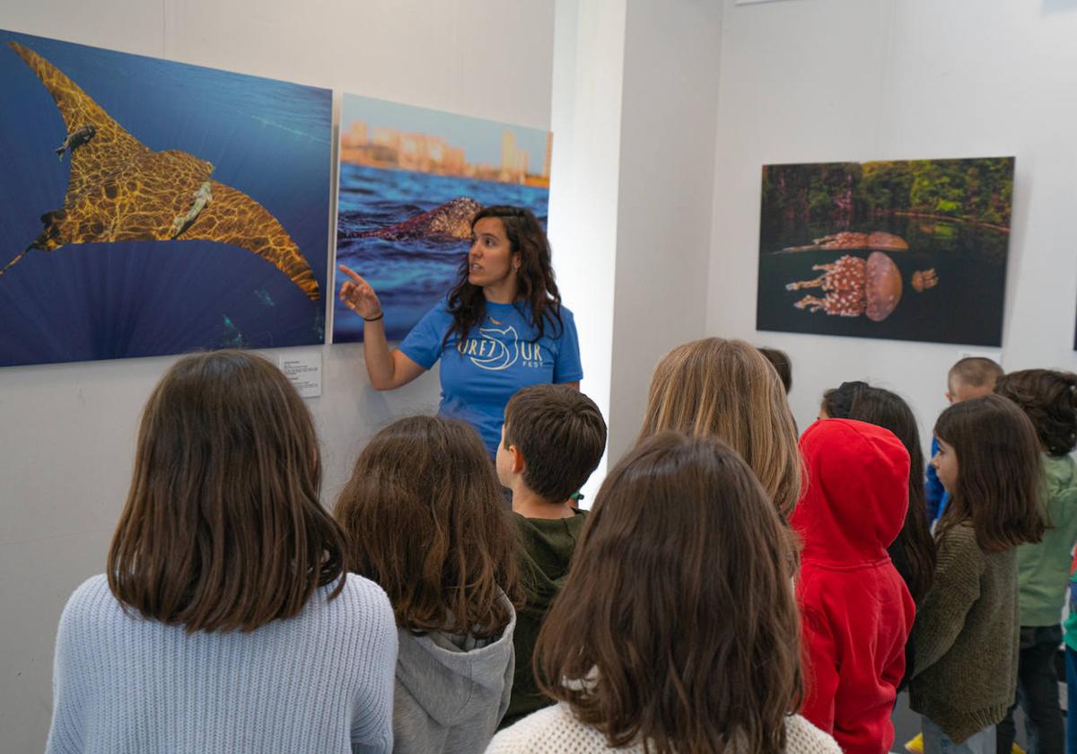 Varios niños escuchan la descripción de una fotografía del fondo marino.