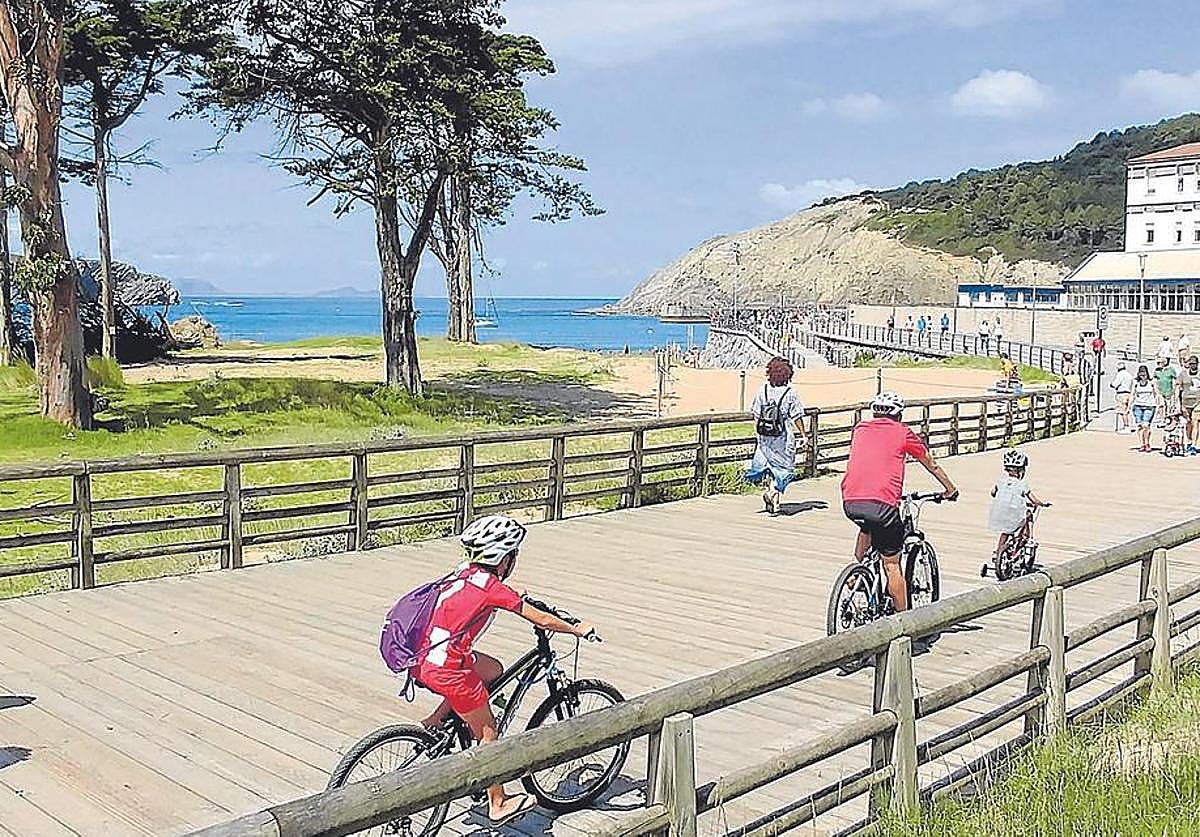 Una familia pasea en bicicleta por la playa de Gorliz.