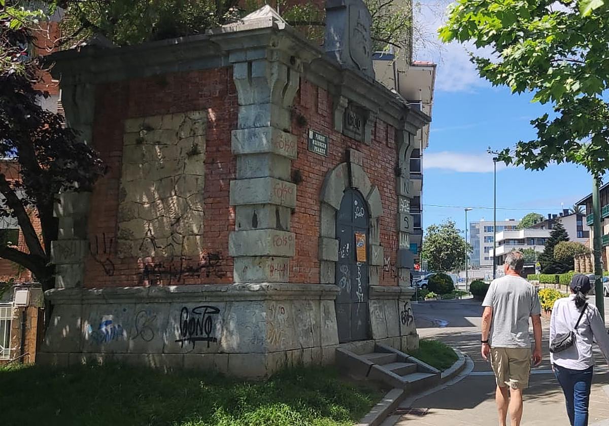 Dos personas pasean junto a una de las edificaciones industriales conocidas como malacates.