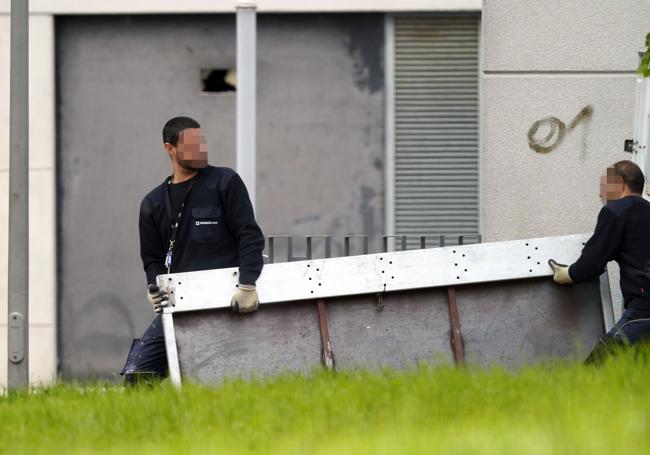 Operarios transportan una puerta antiokupas para colocar en la vivienda recuperada.