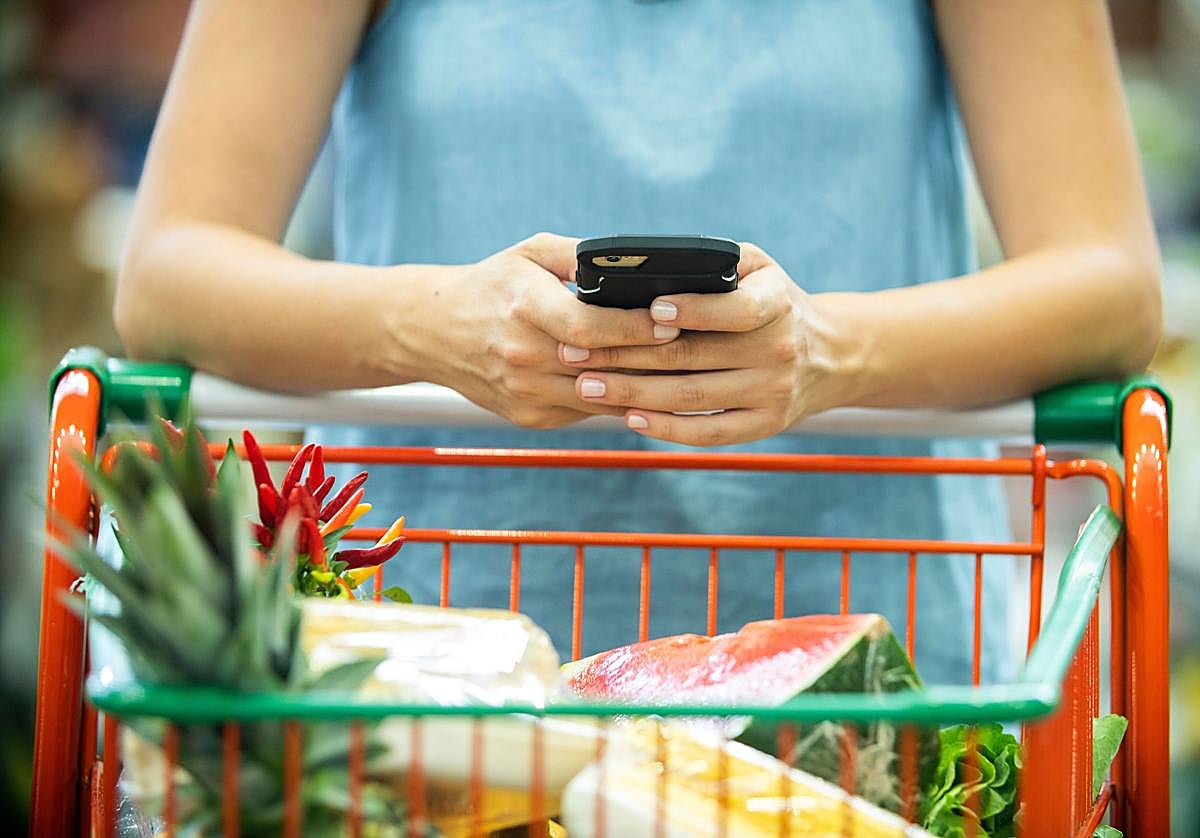 Una mujer recibe un mensaje con ofertas personalizadas mientras realiza la compra en el supermercado.