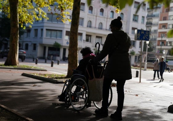 Una mujer y su cuidadora pasean por el parque de Doña Casilda de Bilbao.