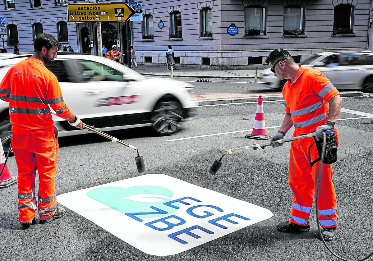 Operarios dan los últimos retoques al logo que avisa, antes de entrar en la Gran Vía desde el Sagrado Corazón, de que se accede a la zona de bajas emisiones.