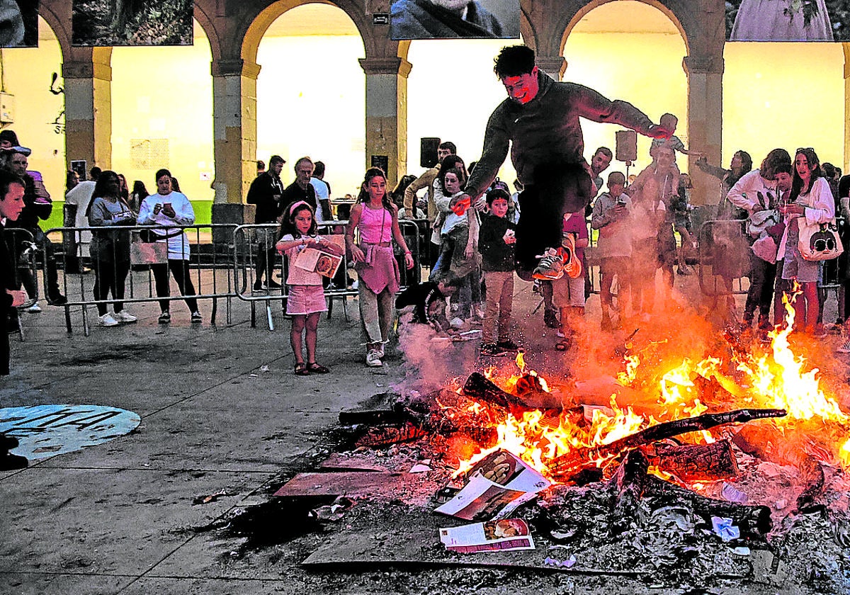 Un joven salta encima del fuego en la hoguera de San Juan de la plaza de San Nicolás de Algorta.