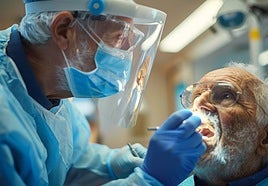 Un odontólogo explora la boca de un paciente en busca de piezas dentales dañadas y de posibles tumores.