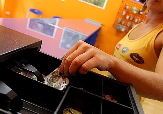 Una camarera ajena a la información saca dinero de la caja registradora.