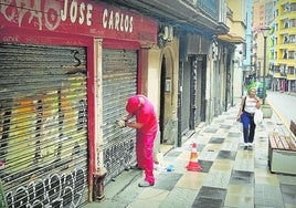 Operarios municipales raspaban ayer las pintadas que afean muchas lonjas de la calle.
