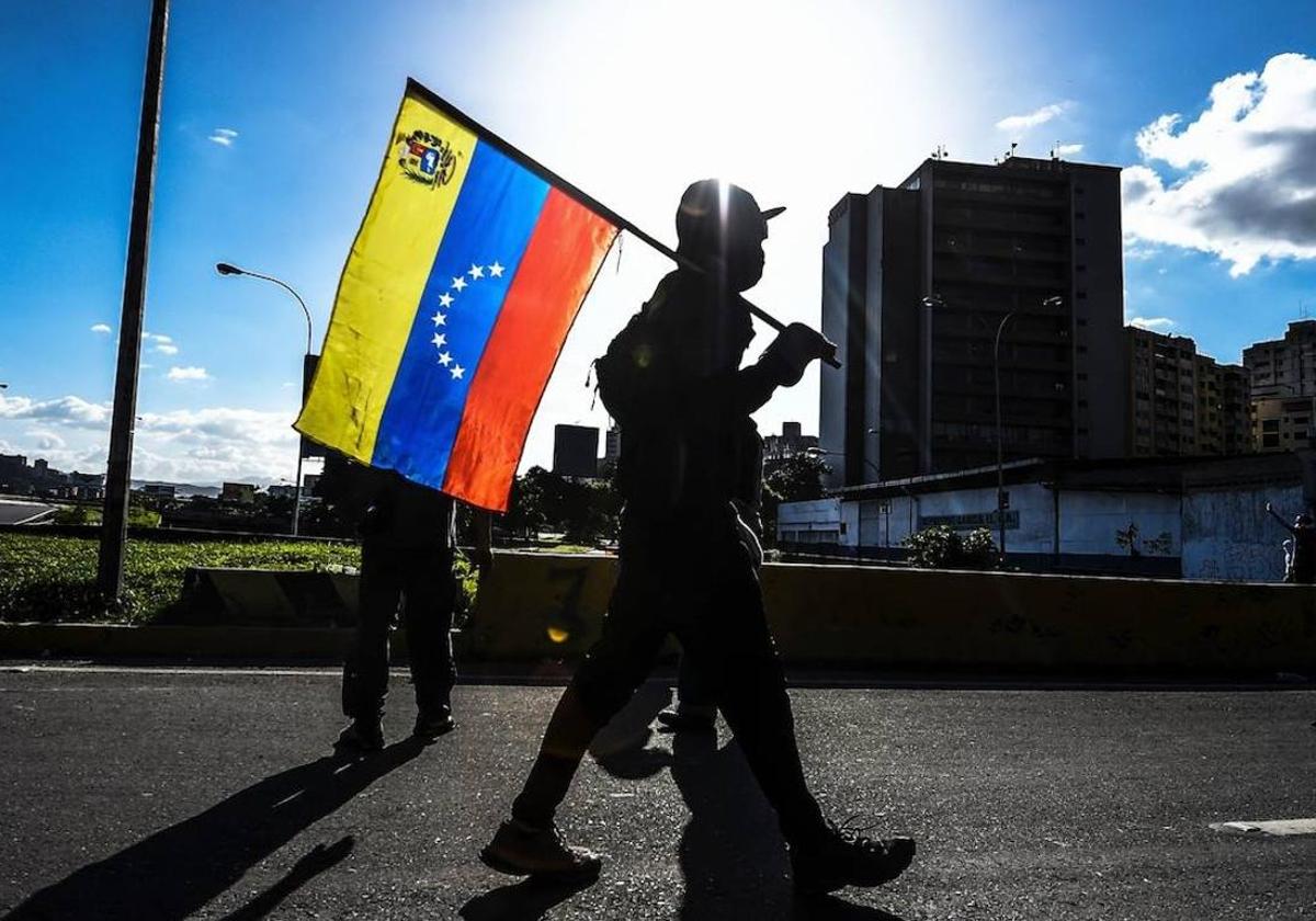 Una persona porta la bandera de Venezuela en las calles del país.