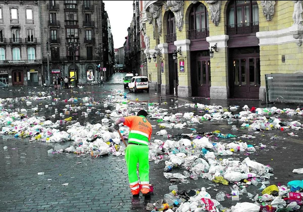 Un operario del servicio municipal de limpieza barre cientos de botellas y bolsas de plástico