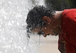 Un hombre se refresca en una fuente de Córdoba.