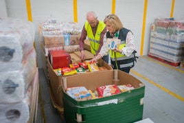 Daniel Fernández organiza junto con una voluntaria varios productos en almacén del Banco de Alimentos.