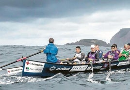 La 'Bou Bizkaia' navega de popa a la ola en dirección al puerto de Bermeo, con la isla de Izaro y Ogoño al fondo.