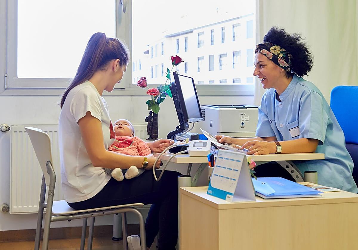 Un bebé, con su madre, en la consulta de la pediatra.