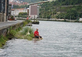 Un hombre se remoja los pies en la ría.