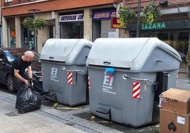 Un vecino tira la basura de un comercio en los contenedores de residuos de Erandio.