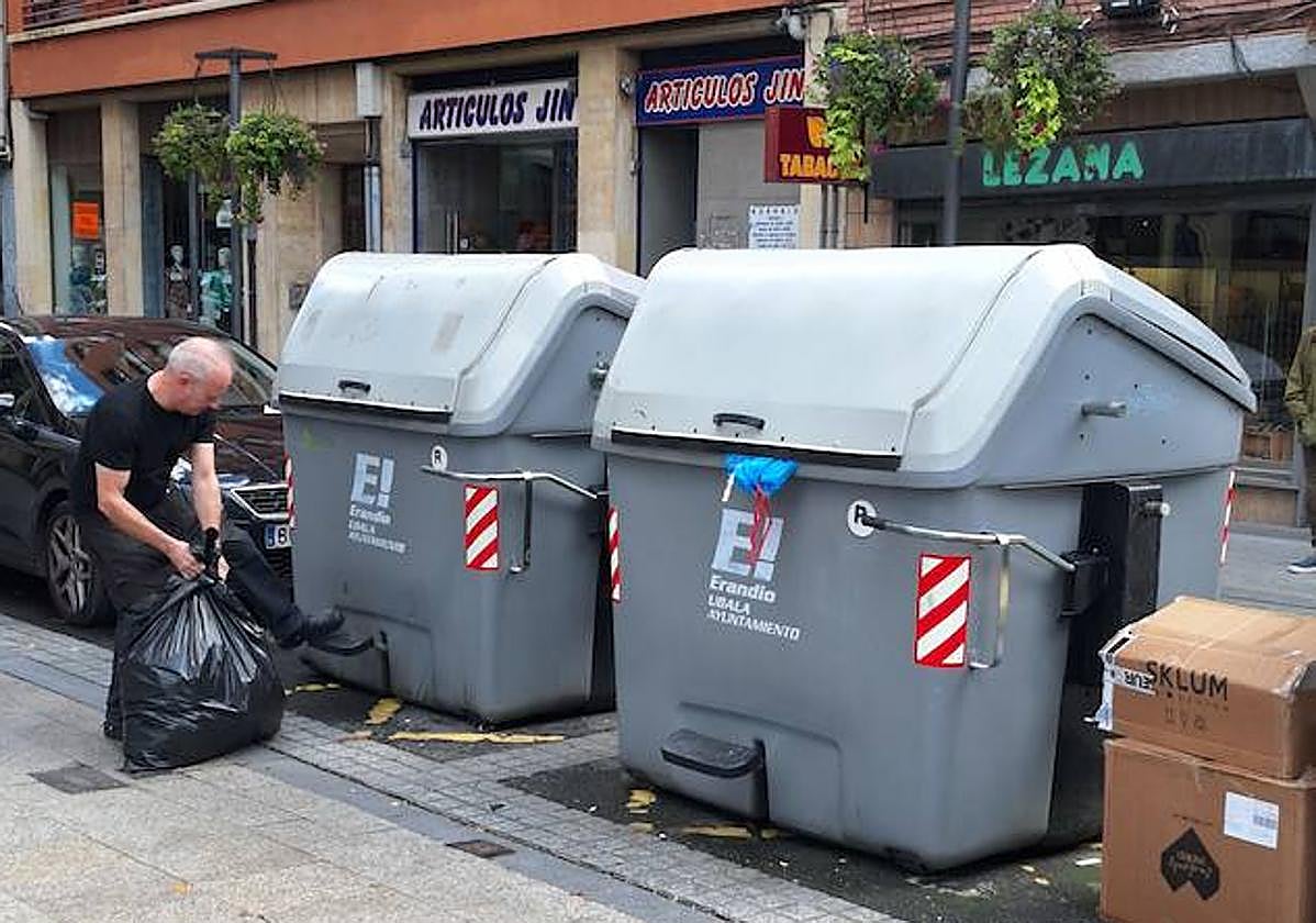 Un vecino tira la basura de un comercio en los contenedores de residuos de Erandio.