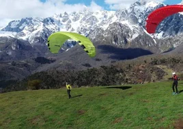 Foto de dos parapentistas con Picos de Europa de fondo.