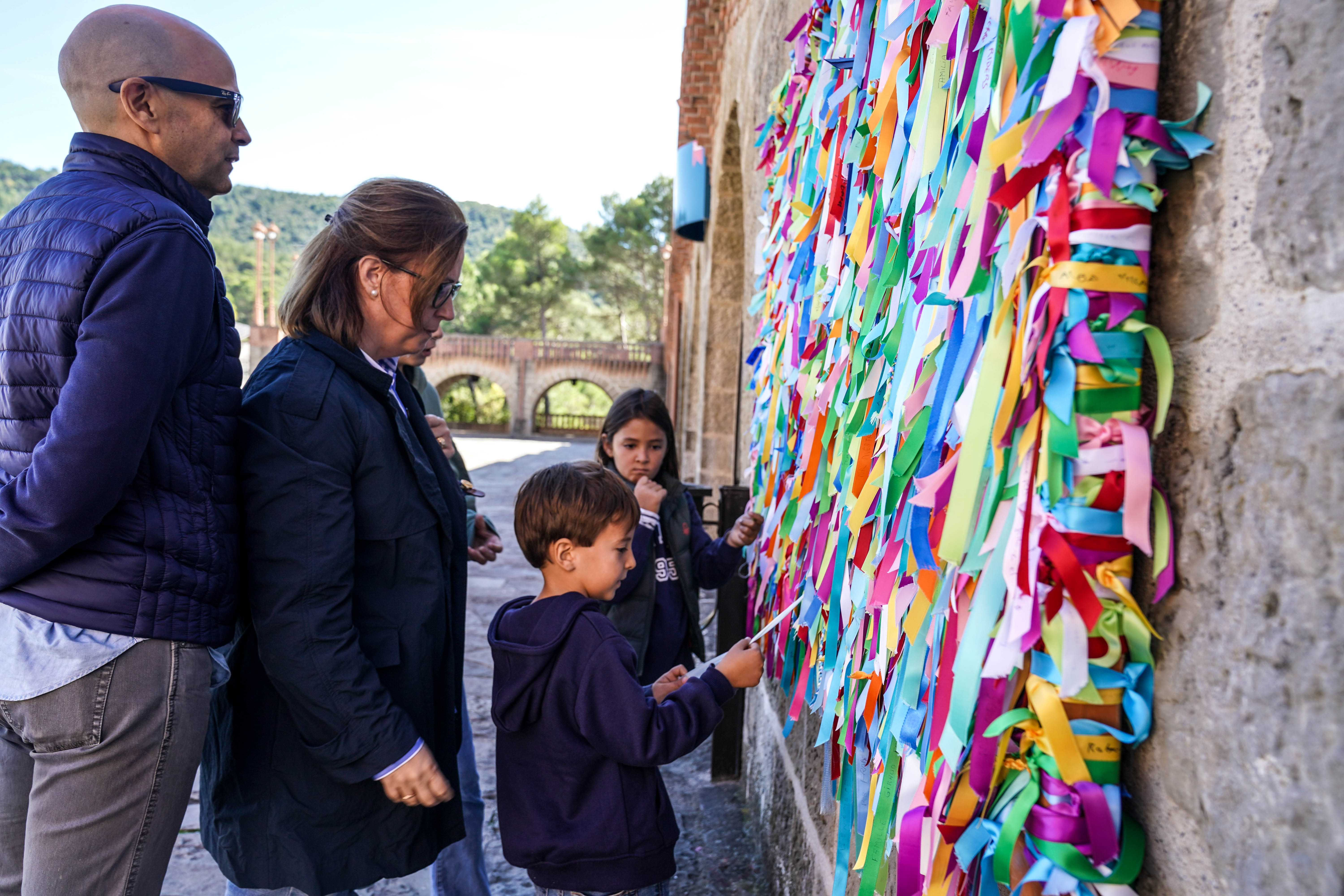 Una familia zaragozana mira las cintas en las que los visitantes manifiestan problemas y deseos a la Virgen.