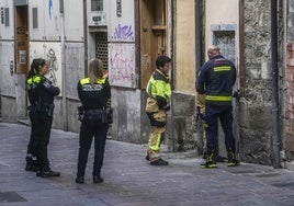 Agentes locales escoltan a los bomberos durante el cierre de una lonja okupada en la calle Santo Domingo. La escena corresponde al viernes.