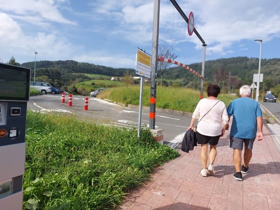 Dos vecinos caminan por delante de uno de los aparcamientos disuasorios de Lekeitio.