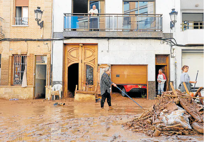 Varias personas limpian una calle de Paiporta.