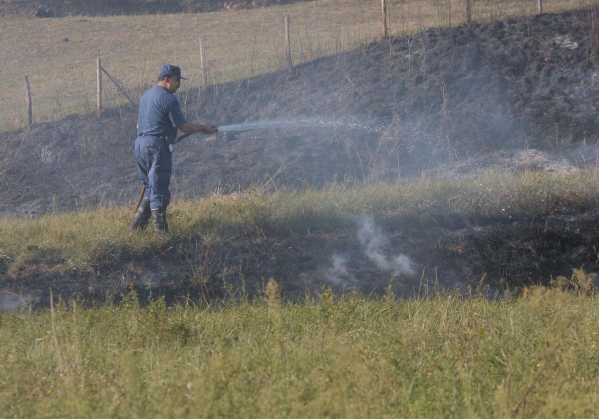 Un agricultor ajeno a los hechos refresca un terreno donde quema rastrojos.