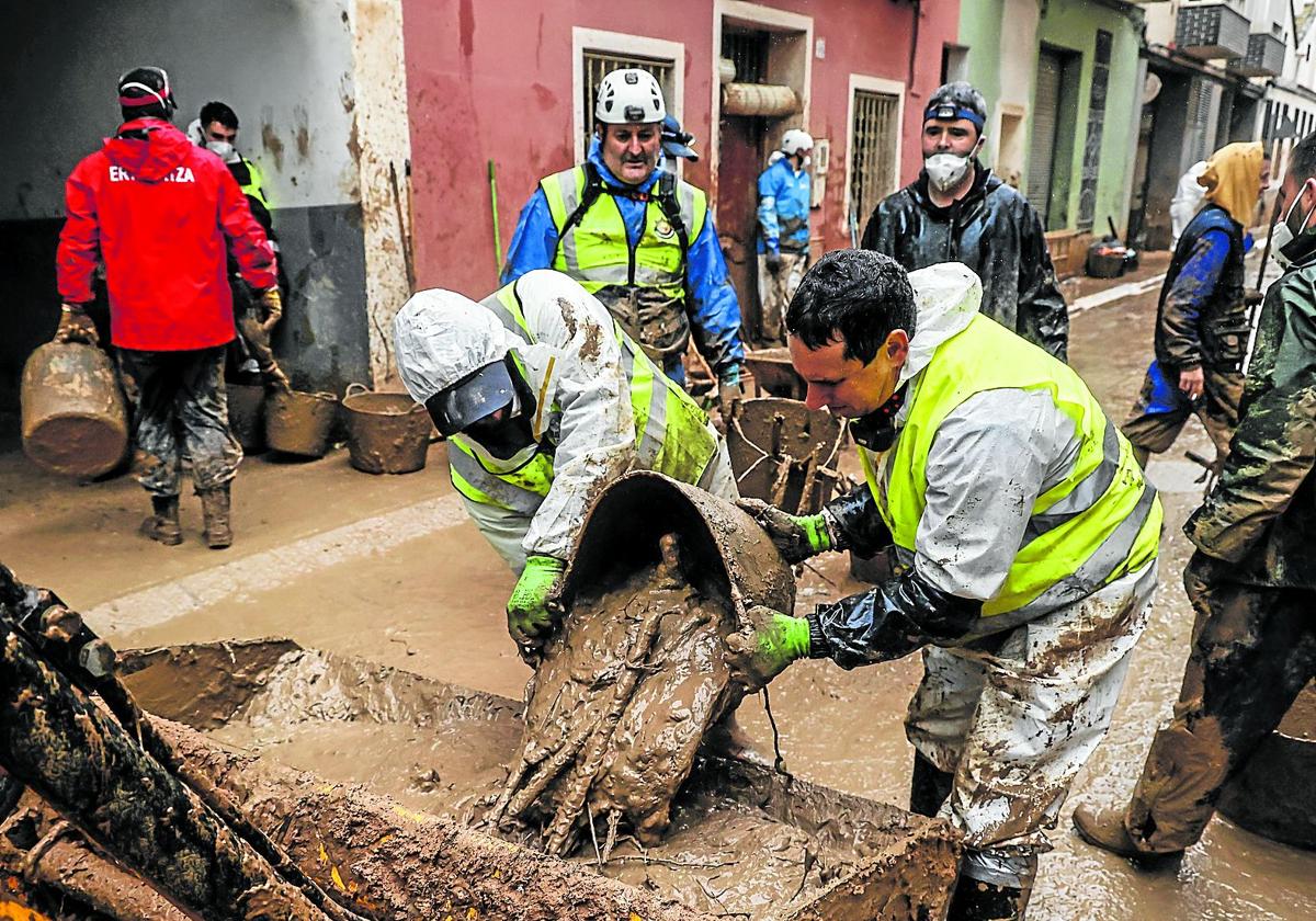 Voluntarios intentan desatascar alcantarillas y acequias en la localidad valenciana de Paiporta.