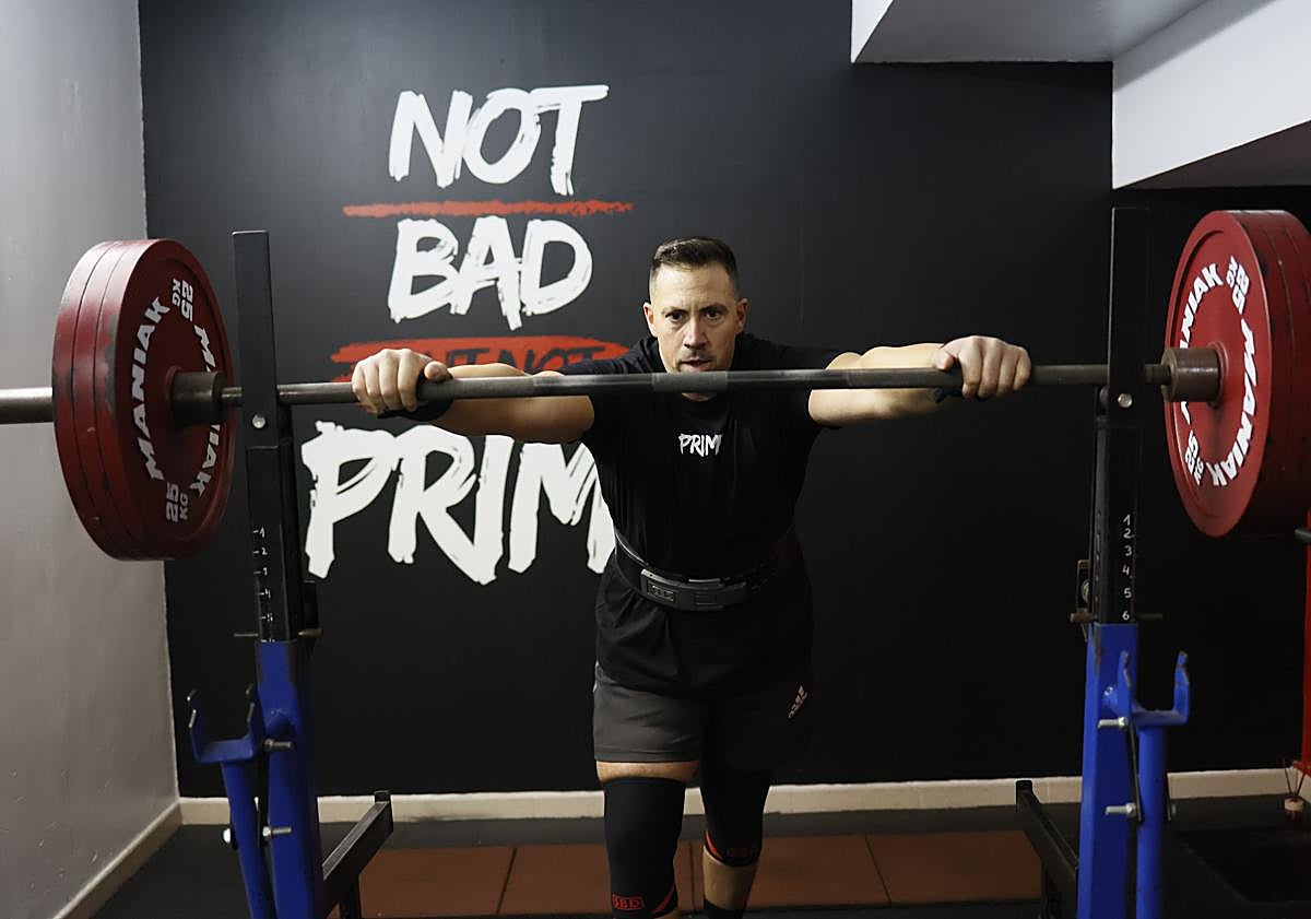 Imagen principal - Jorge se prepara para hacer sentadillas. En la siguiente foto, con la medalla conseguida en el campeonato de España. En la última imagen, junto a una de las enormes cadenas con las que trabaja.