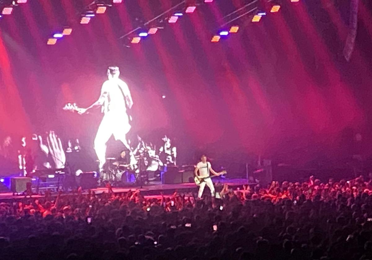 Bryan Adams, con pantalón y camiseta blanca en contraste con su banda enlutada.