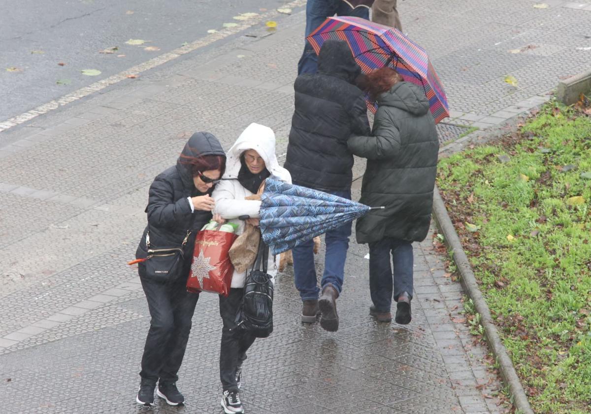 Varias personas se protegen del viento y la lluvia este sábado en Bilbao.