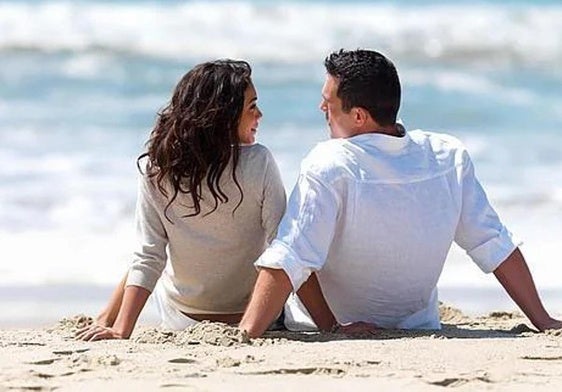 Una pareja de enamorados se declara su amor sobre la arena de la playa.