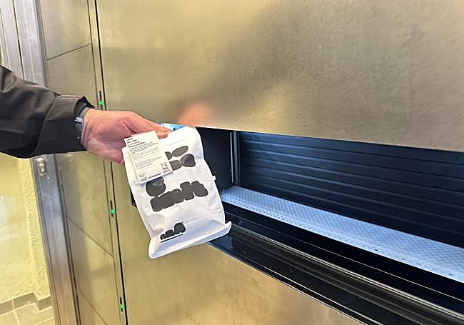 Un cliente coge unas cookies de la máquina expendedora.