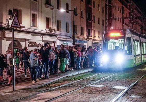 Usuarios del tranvía esperan la llegada del convoy durante una noche de fiestas de La Blanca.