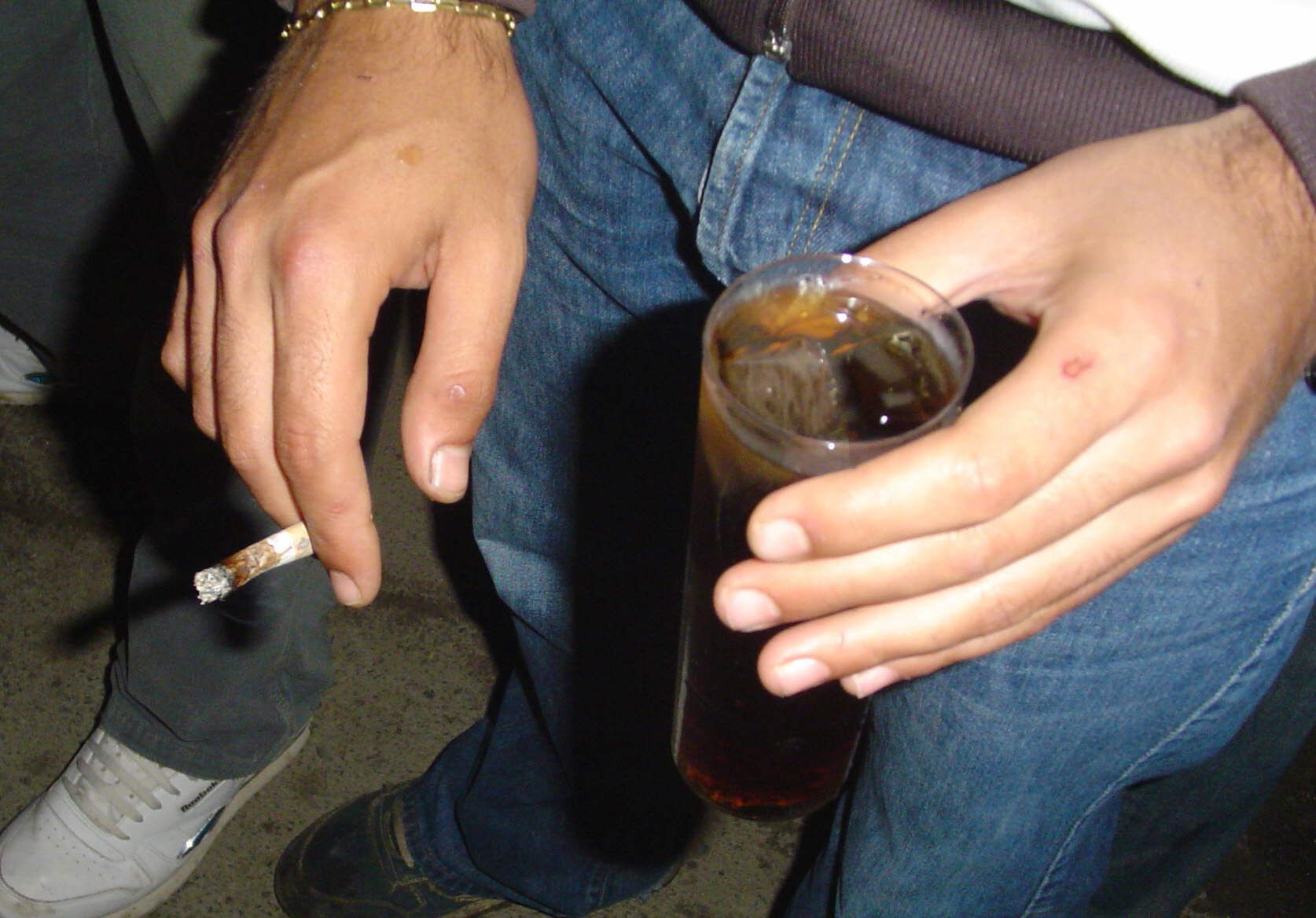 Un joven se bebe un cubata mientras se fuma un porro de marihuana, una combinación explosiva para la salud, especialmente de su cerebro.