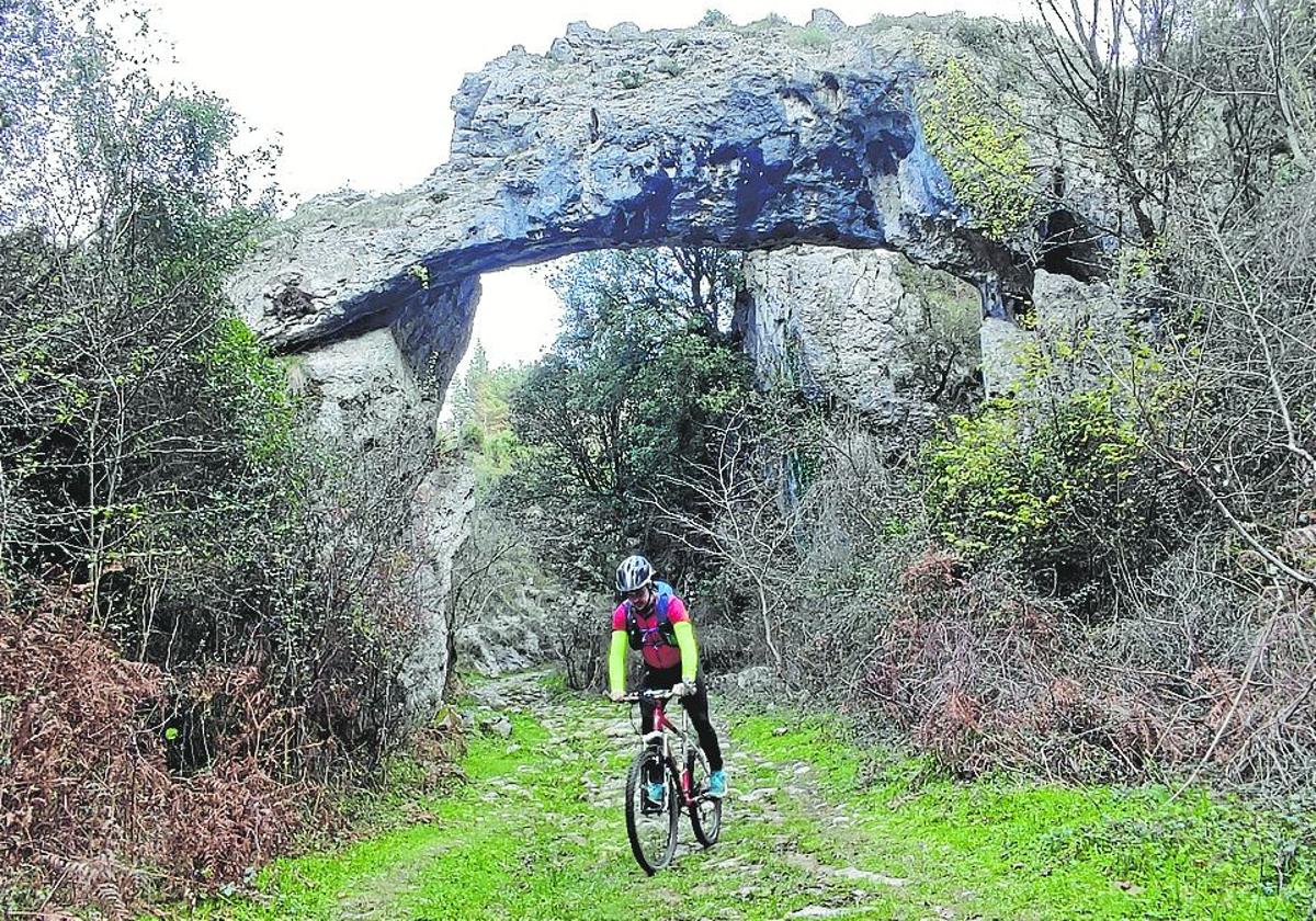 Un ciclista pasa bajo el arco de piedra de Jentilzubi.