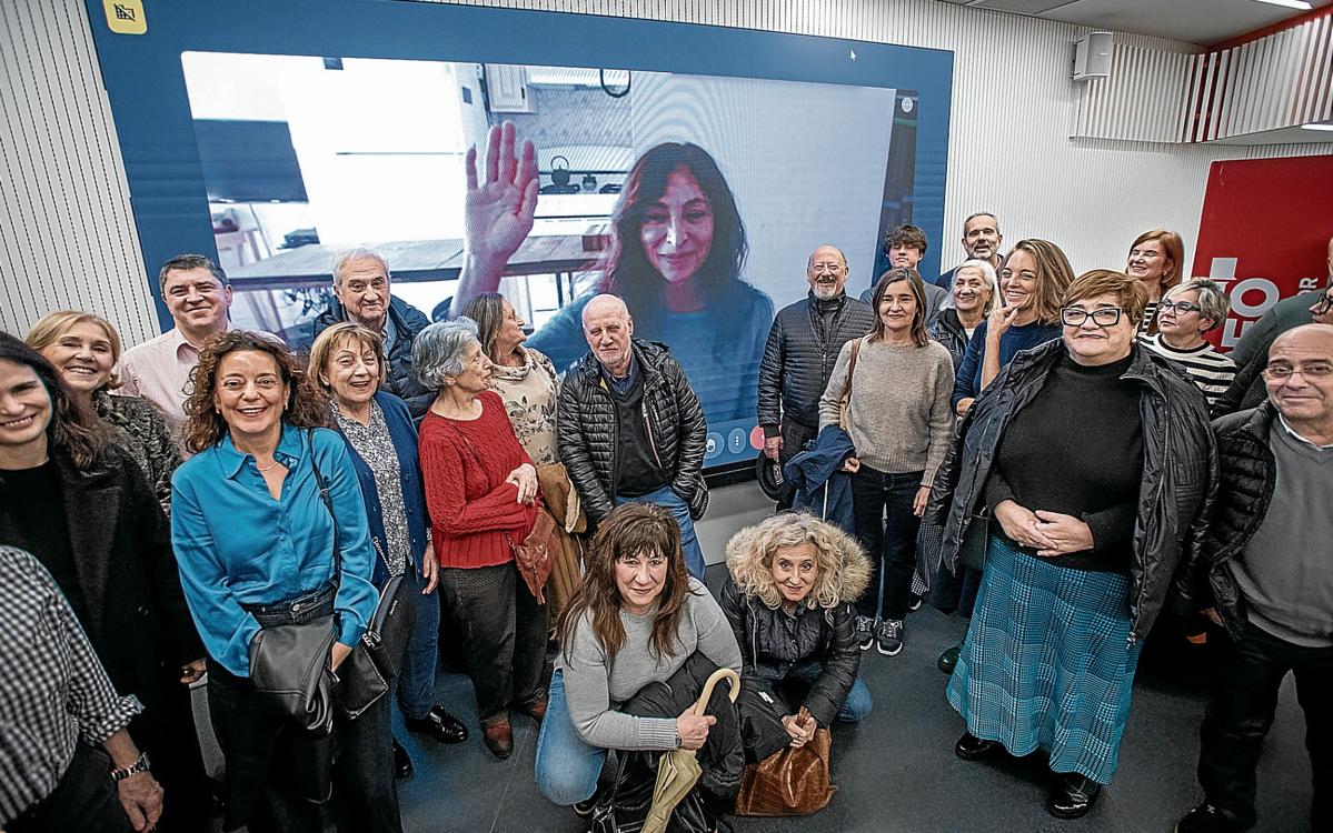 Varios participantes en el encuentro con suscriptores posan ante la pantalla, desde la que saluda Mercedes Gallego.