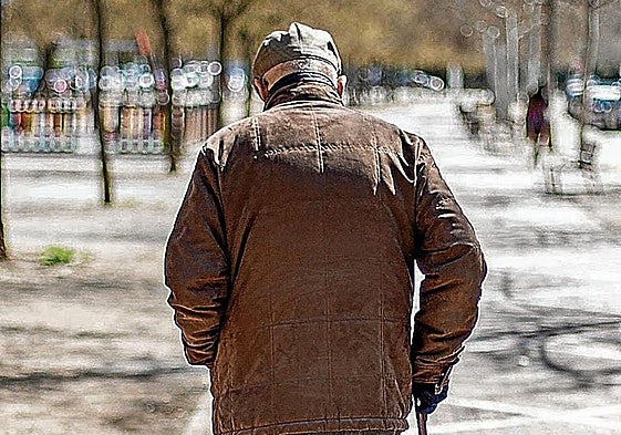 Un anciano camina bajo el sol.