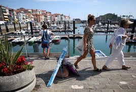 Un niño se soma al puerto de Lekeitio mientras dos mujeres se dirigen a la playa.