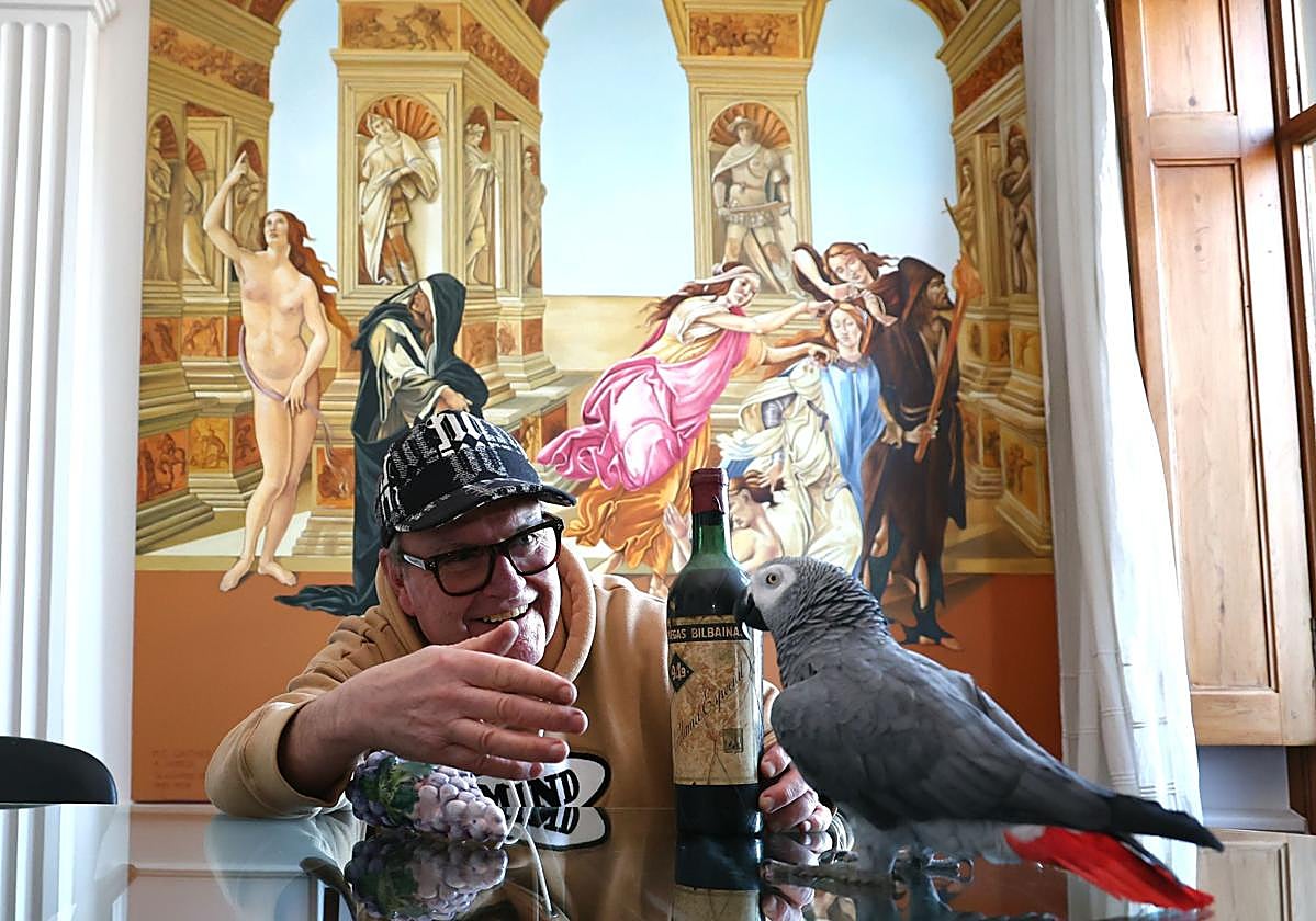Rafael García Santos en su casa donostiarra con 'Gorri', el loro que le acompaña desde hace 40 años, y con una botella de Bilbaínas (1949) que compró en su época de militancia sindicalista.