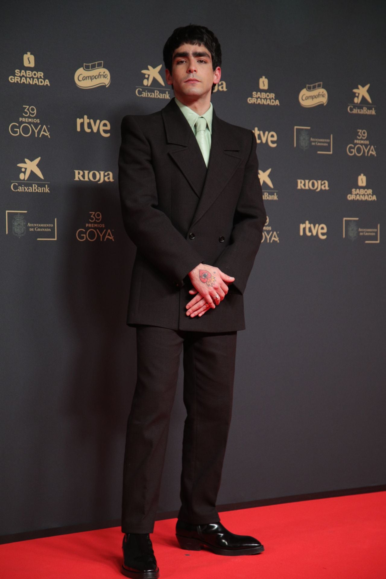 Conocido por su papel en la exitosa serie 'Élite', el actor Omar Ayuso ha posado en los Goya con un look de Bottega Veneta con camisa y corbata en verde agua que refleja su estilo moderno y rompedor.