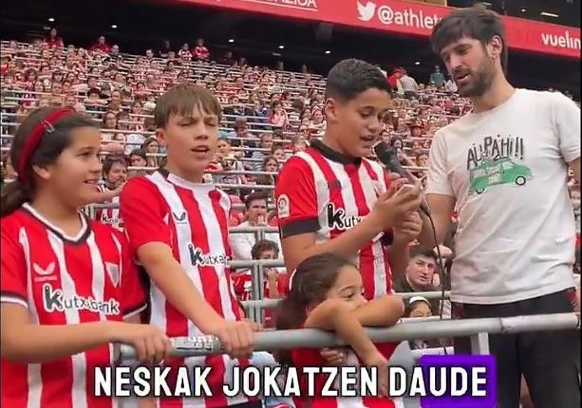 Un niño canta en la grada un bertso dedicado al Athletic mientras el humorista Julen Axpe le sostiene el micrófono.