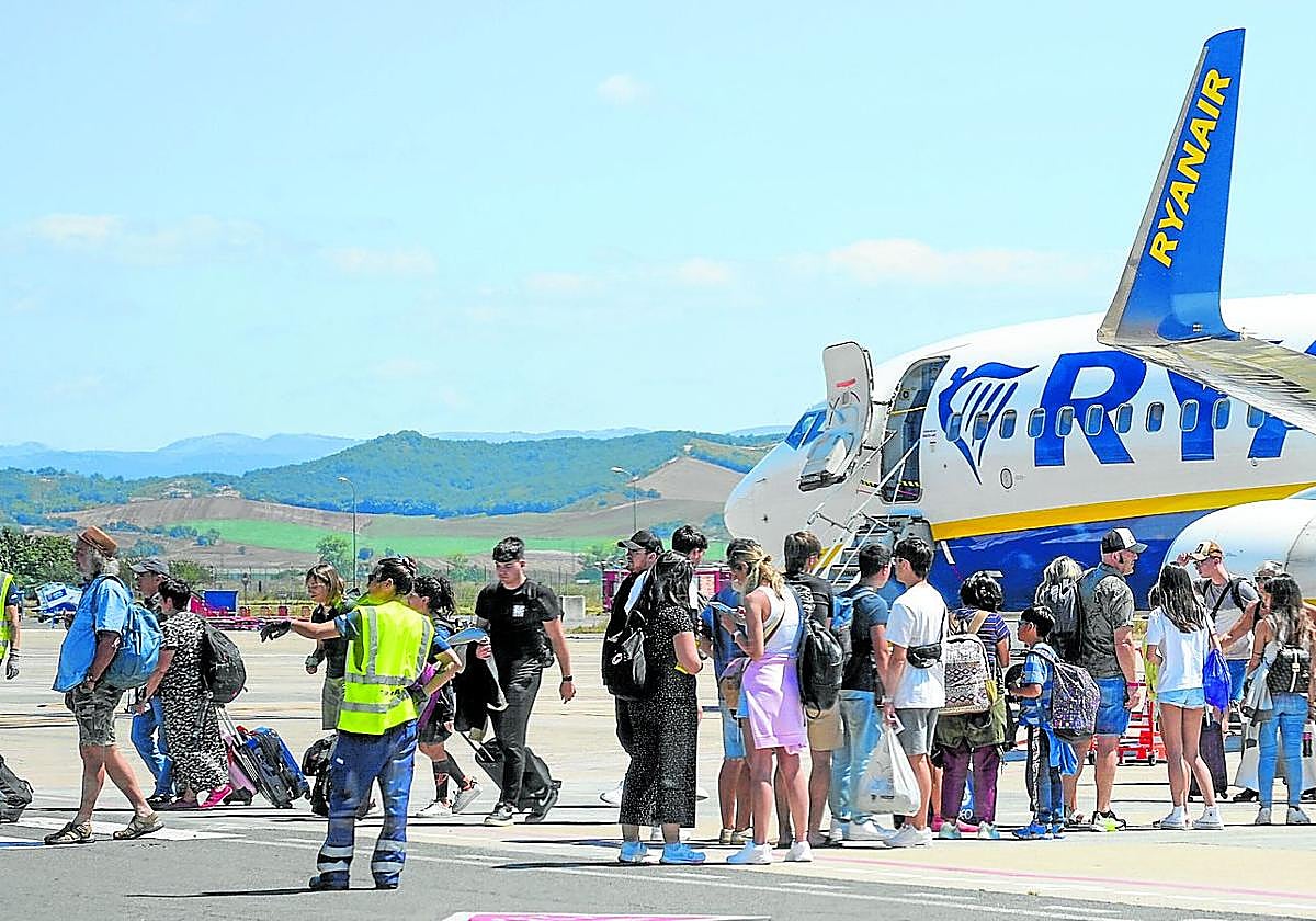 Pasajeros en el aeropuerto de Vitoria junto a un avión de Ryanair, que desplegará un cartel con seis destinos desde finales de marzo.